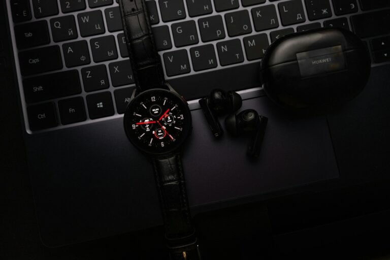 Smartwatch earbuds and laptop representing AI wearables in 2026